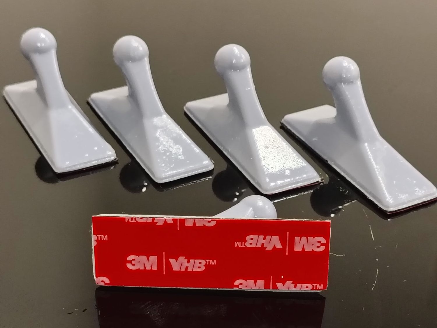 Five white 3D printed resin coat hooks with a 3M VHB double-sided adhesive pad